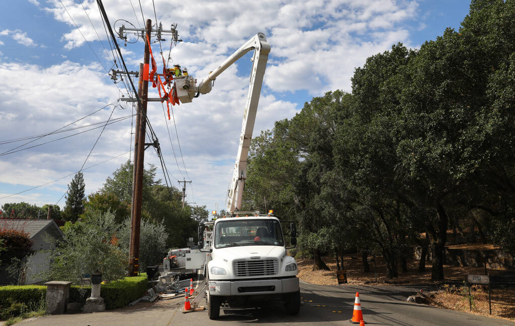 A journeyman linemen from Rokstad, contracted by PG&E, works on moving power lines to a new pole and installs a sectionalizer along Brush Creek Road near Montecito Boulevard in Santa Rosa on Friday, Aug. 14, 2020.  (Christopher Chung / The Press Democrat)