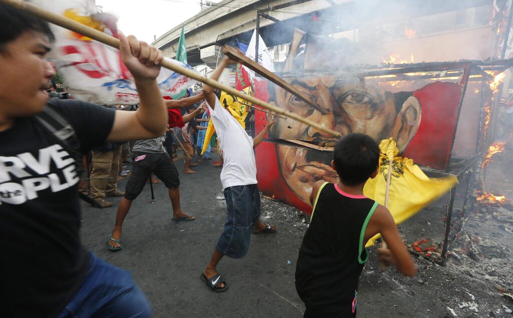 Protesters hit the burning cube effigy with the faces of the late dictator Ferdinand Marcos and President Rodrigo Duterte during a rally near the Presidential Palace to call for an end to the killings in the so-called war on drugs of Duterte and his alleged 'tyrannical rule' in the country Thursday, Sept. 21, 2017 in Manila, Philippines. Thousands of protesters are marking the anniversary of the 1972 martial law declaration by late Philippine dictator Ferdinand Marcos with an outcry against what they say is the current president's authoritarian tendencies and his brutal crackdown on illegal drugs. (AP Photo/Bullit Marquez)