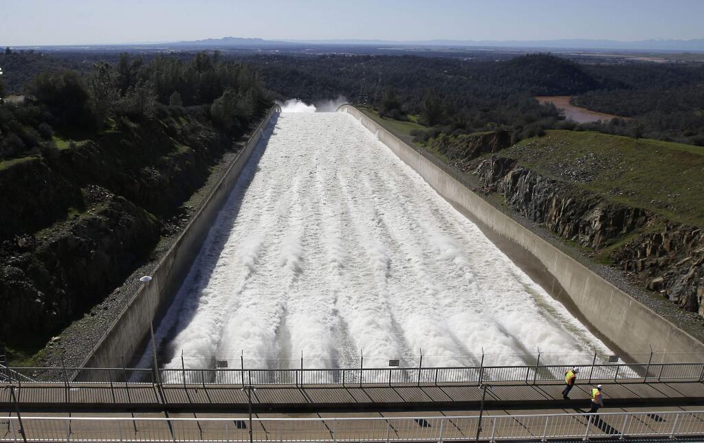 In this Saturday, Feb. 11, 2017, photo, water flows down Oroville Dam's main spillway, in Oroville, Calif. Water began flowing over the emergency spillway on Saturday for the first time in its nearly 50-year history after heavy rainfall. In addition to the emergency spillway, water also flowed through the main spillway that was significantly damaged from erosion. Officials said they'll assess the damage starting Monday. (AP Photo/Rich Pedroncelli)
