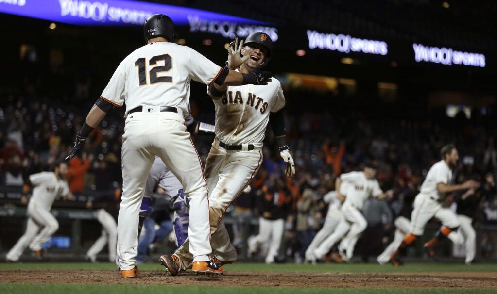 San Francisco Giants' Gorkys Hernandez, right, celebrates with Joe Panik (12) after scoring the game winning run against the Colorado Rockies in the 14th inning of a baseball game Tuesday, June 27, 2017, in San Francisco. Hernandez scored on a single by Giants' Denard Span. (AP Photo/Ben Margot)