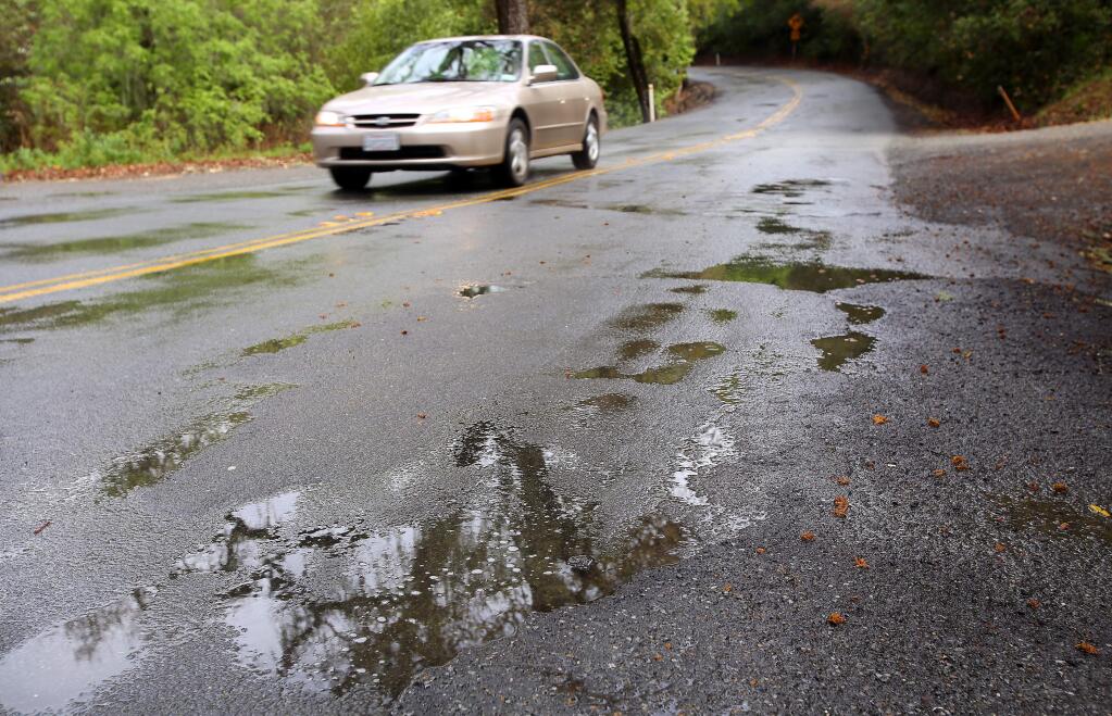A vehicle passes potholes filled with rainwater along Bennett Valley Road, between Old Bennett Ridge Road and Warm Springs Road, in Santa Rosa on Tuesday, March 25, 2014. (Christopher Chung/ The Press Democrat)