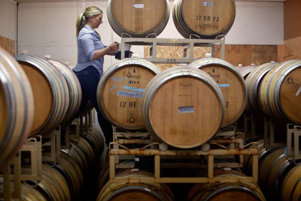 Winemaker Erica Stancliff tops off barrels of pinot noir wine at Furthermore Wines in Sebastopol, California, on Monday, June 12, 2017. (Alvin Jornada / The Press Democrat)
