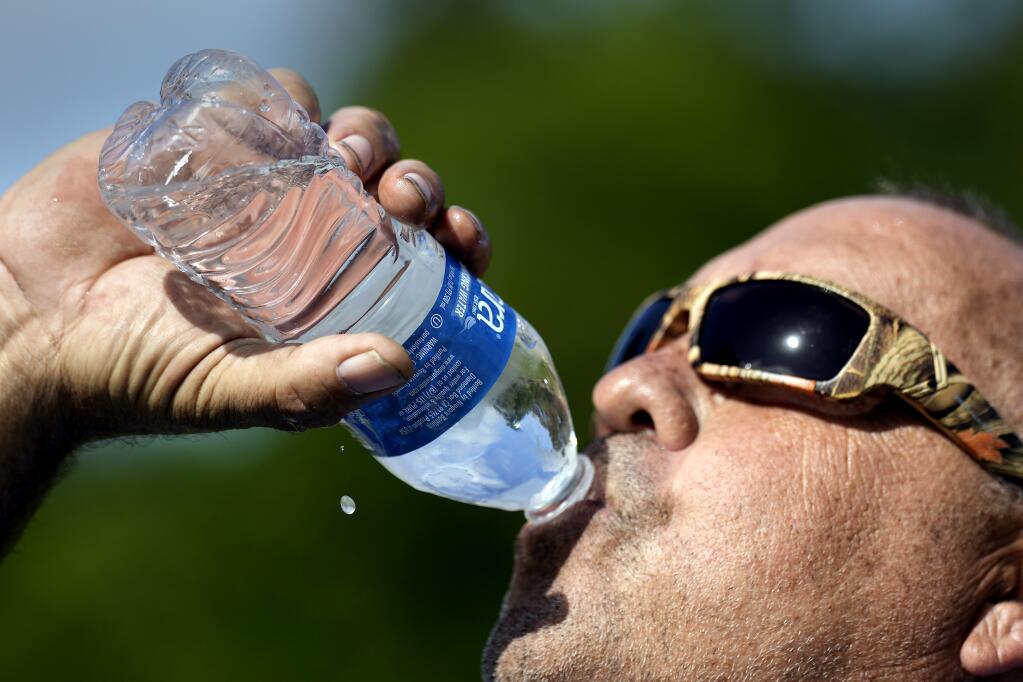Robert Harris drinks water while taking a break from digging fence post holes, Tuesday, June 27, 2023, in Houston. (AP Photo/David J. Phillip)