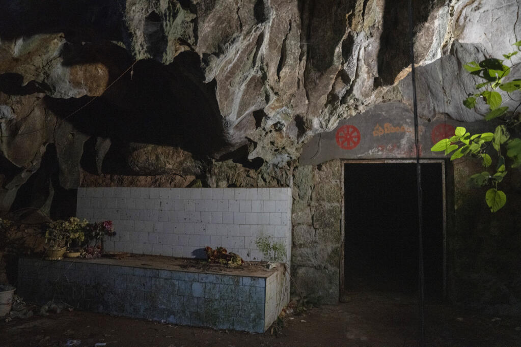The entrance to the abandoned Wanling cave is littered with religious paraphernalia near Manhaguo village in southern China's Yunnan province on Wednesday, Dec. 2, 2020. Villagers said the cave had been used as a sacred altar presided over by a Buddhist monk, precisely the kind of contact between bats and people that alarms scientists. (AP Photo/Ng Han Guan)