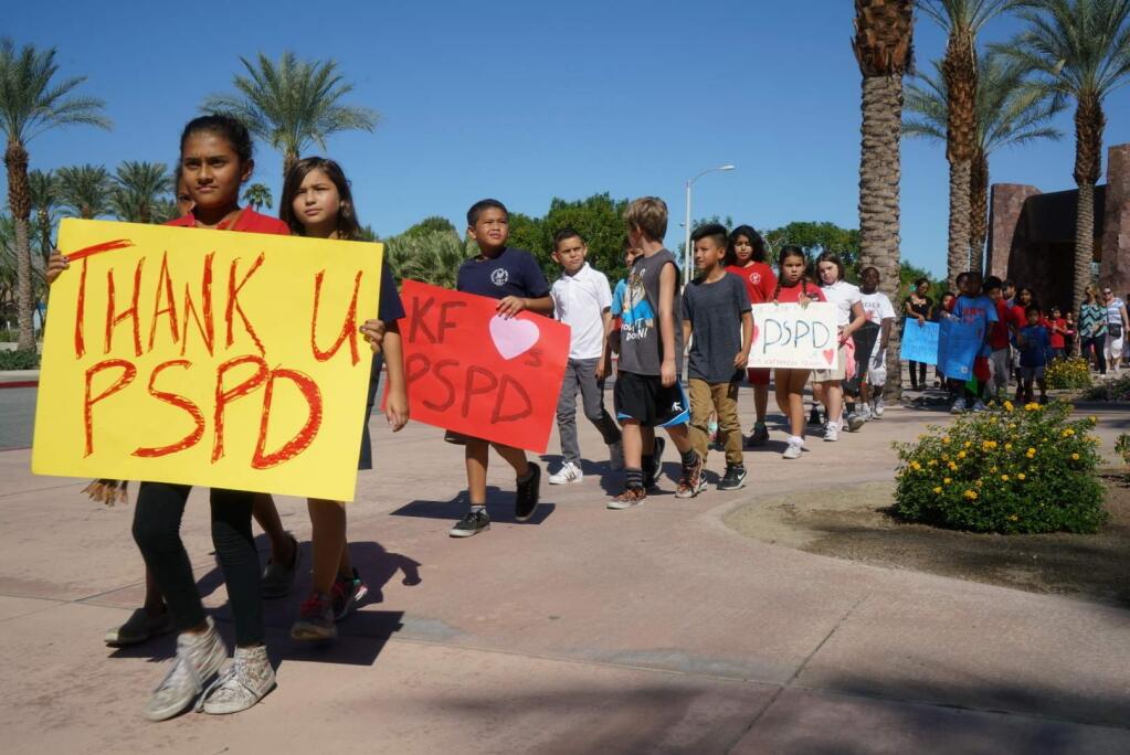 Fourth-graders from Katherine Finchy Elementary School walk outside the Palm Springs Convention Center, showing signs of support for the two fallen police officers, Gil Vega and Lesley Zerebny, before a memorial service for the officers, Tuesday, Oct. 18, 2016, in Palm Springs, Calif. The two were ambushed and gunned down during an Oct. 8 domestic disturbance call. (Zoe Meyers/The Desert Sun via AP)