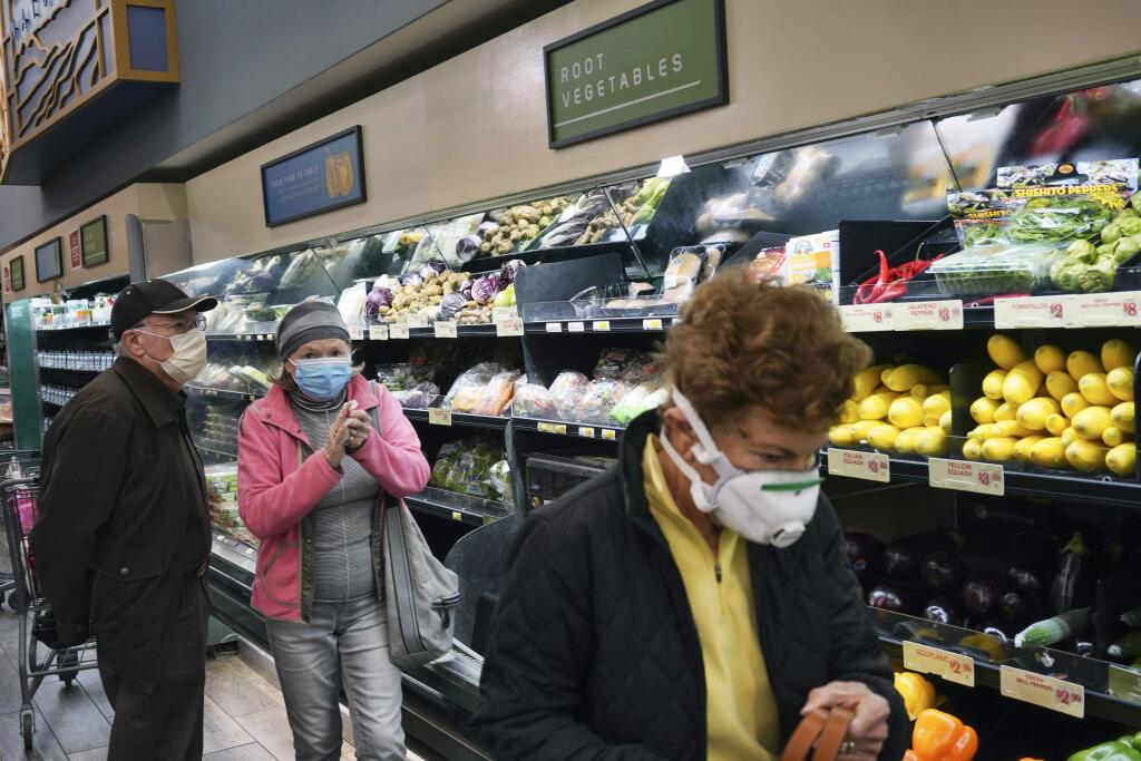 FILE - In this March 20, 2020, file photo, customers wear protective masks while shopping for groceries in the Sherman Oaks section of Los Angeles. Los Angeles Mayor Eric Garcetti has recommended that the city's 4 million people wear masks when going outside amid the spreading coronavirus. (AP Photo/Richard Vogel, File)