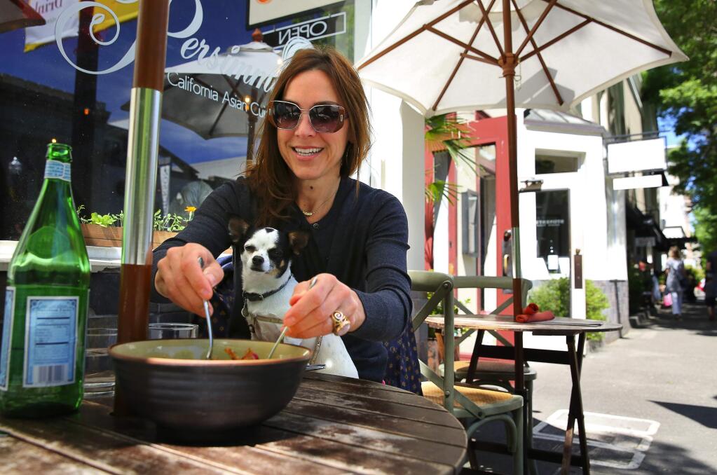 Stephanie Culen eats with her dog, Bianca Uma Devi, sitting on her lap at Persimmon, in Healdsburg on Friday, April 28, 2017. (Christopher Chung/ The Press Democrat)