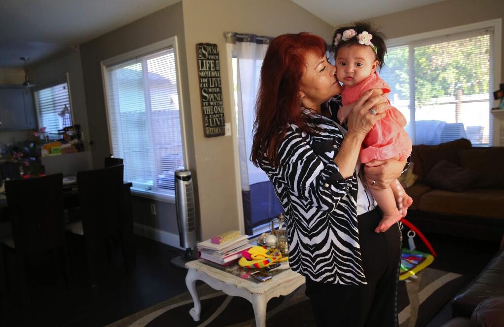 Maria Ramirez, 56, holds her 5-month-old granddaughter, Karli Elias de Paz, at her home in Santa Rosa, on Tuesday, October 18, 2016. Ramirez became a citizen and registered to vote in May, in order to participate in her first presidential election, with the hope that she can help defeat Donald Trump. (Christopher Chung/ The Press Democrat)