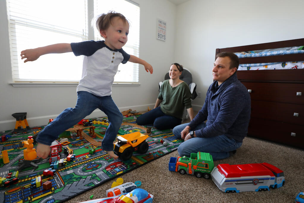 Jason and Mandy Flynn watch their three-year-old son Declan, 3, jump and dance as his toy plays a song, at their home in Windsor on Monday, March 15, 2021.  The Flynn's bought their home at the end of January, 2020.  (Christopher Chung/ The Press Democrat)