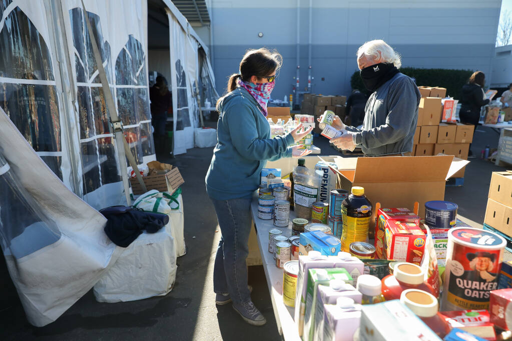 Denise and Rick Degraf sort donated food at Redwood Empire Food Bank in Santa Rosa on Monday, Nov. 23, 2020.  (Christopher Chung/ The Press Democrat)