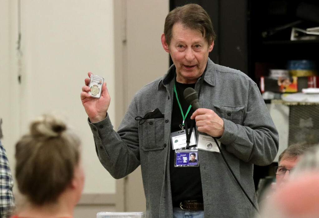 Joe McCarthy of Santa Rosa, holds a 1970 Eisenhower silver dollar while pointing out a scratch was detected on his that lowered the value, during a Redwood Empire Coin Club monthly meeting at Santa Rosa Veterans Memorial Building, Wednesday, Feb. 8, 2023, in Santa Rosa. (Darryl Bush/For The Press Democrat)