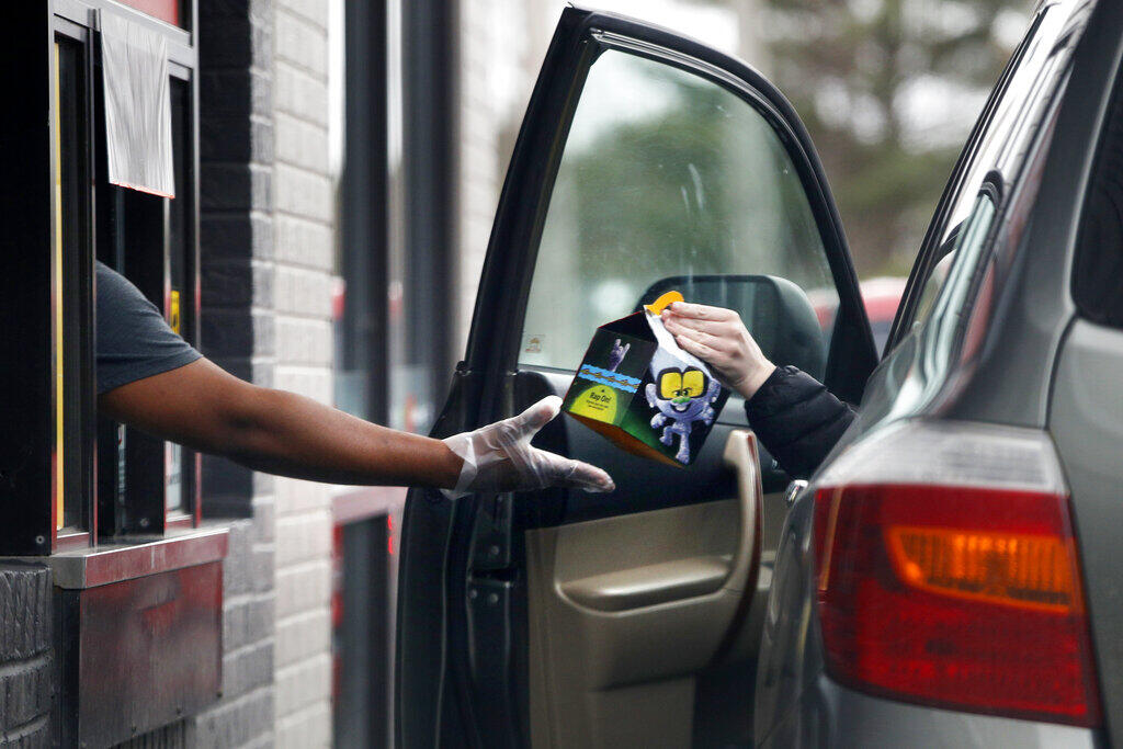 A worker at McDonalds hands a customer a Happy Meal. (ROBERT F. BUKATY / Associated Press)