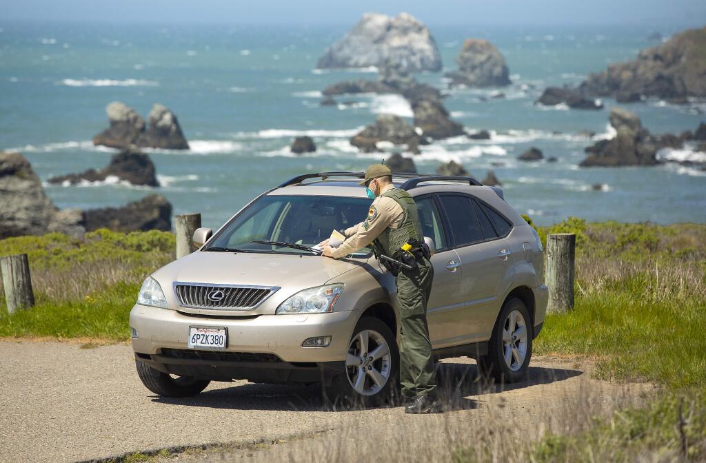 State Parks supervising ranger Damien Jones places a $51.50 ticket on a car parked at an access point for the Kortum Trail off Hwy 1 north of Bodega Bay on Friday. Rangers have an option for increasing fines depending on the violation trying to access coastal areas closed by Covid-19. (photo by John Burgess/The Press Democrat)