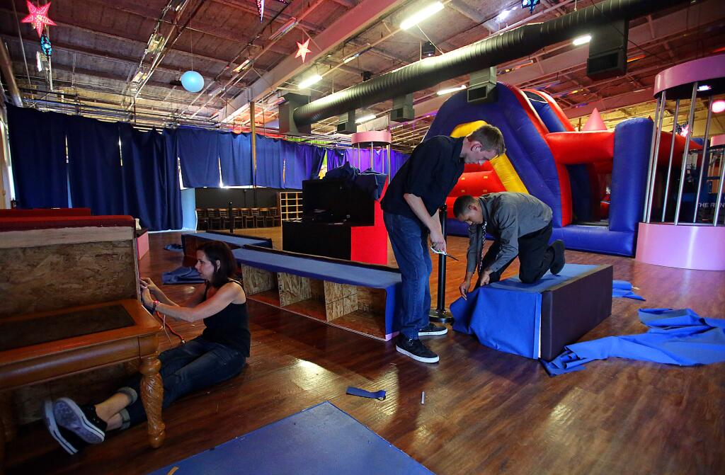 Sachi Woods, left, Mason Woods, center and Jordan Castaneda, right, attach fireproof fabric to benches during last minute preparations for opening 'PinkDrift' a nightclub for teens held at La Pinata on Piner Road in Santa Rosa, June 26, 2014. The city on Wednesday ordered the La Piñata kids party center on Piner Road to cease operations. (Crista Jeremiason / The Press Democrat)