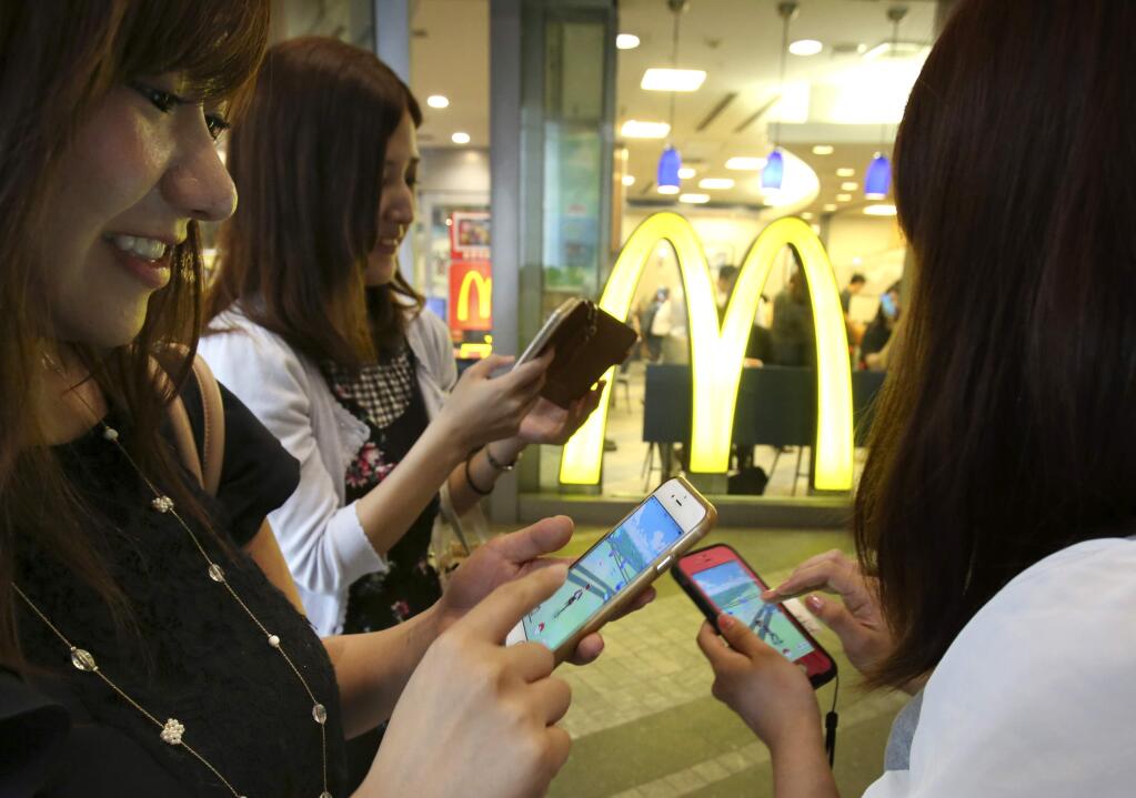 Women play 'Pokemon Go' in front of a McDonald's restaurant in Tokyo, Friday, July 22, 2016. (AP Photo/Koji Sasahara)