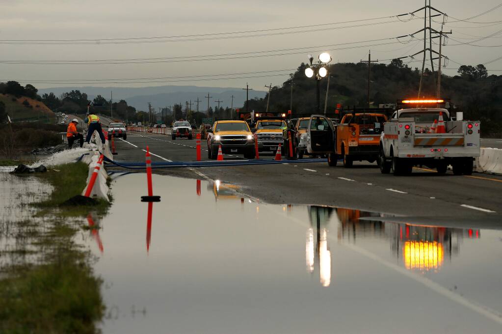 Workers from Cal Trans and Ghilotti Brothers construction check road conditions and pump flood water away from Highway 37 after a levee along Novato Creek was broken, flooding the highway near Novato, California, on Friday, March 1, 2019. (Alvin Jornada / The Press Democrat)