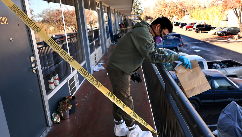 A Sonoma County Sheriff's detective hands off an evidence bag, Tuesday, Dec. 13, 2022, at the scene of a homicide on the second floor of the Palms Inn just outside the Santa Rosa city limits on Santa Rosa Avenue. (Kent Porter/The Press Democrat)