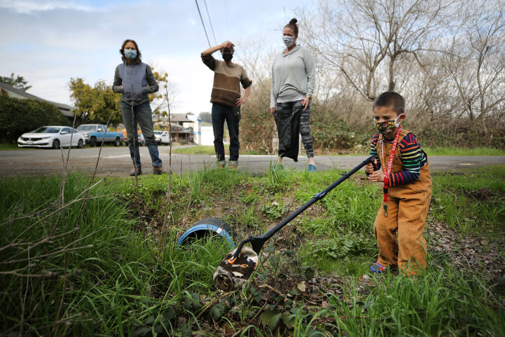 From right, Logan Shmatovich, 5, picks up trash around the corner from Valley Ford Road on Thursday, Feb. 18, 2021. Looking on are members of a new group called Soil Growers, including his grandmother, Niki Shmatovich, Saill White and Terry Church, who will be picking up garbage on a 2 1/2-stretch of Valley Ford Road under a new Sonoma County Adopt A Road program. (Beth Schlanker / The Press Democrat)