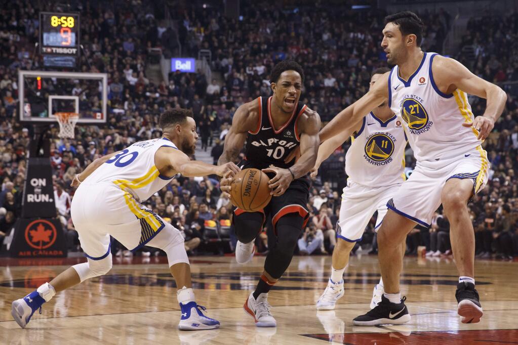 The Toronto Raptors' DeMar DeRozan (10) tries to break through the defense of Golden State Warriors center Zaza Pachulia (27) and guard Stephen Curry (30) during the first half Saturday, Jan. 13, 2018, in Toronto. (Cole Burston/The Canadian Press via AP)