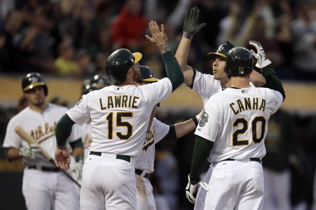 Oakland Athletics' Danny Valencia, second from right, is congratulated by Brett Lawrie (15) and Mark Canha (20) after hitting a grand slam off Seattle Mariners pitcher Edgar Olmos during the first inning of a game Friday, Sept. 4, 2015, in Oakland. (AP Photo/Ben Margot)