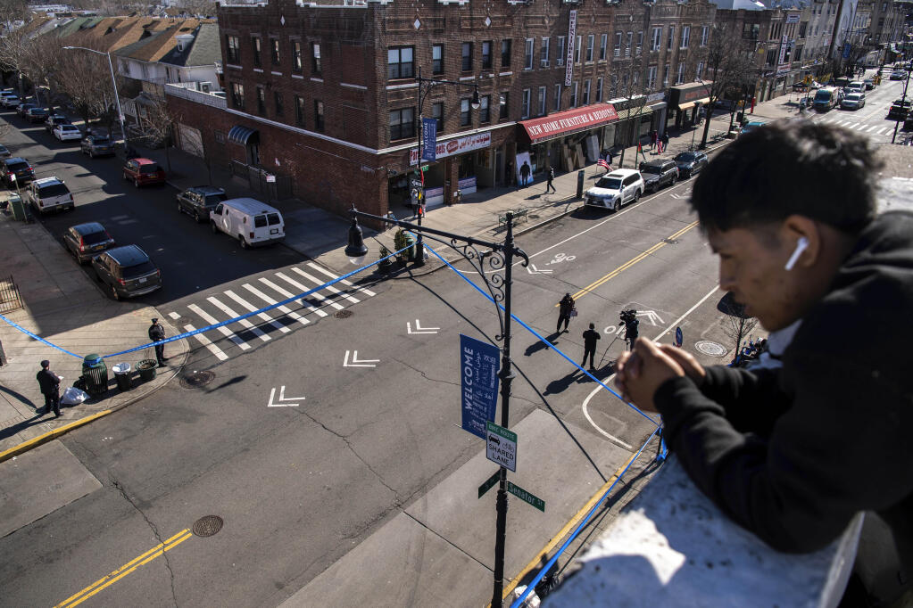 FILE —-Erafin Yaz, 25, looks from his roof at the caution tape covering the corner of Bay Ridge Avenue and 5th Avenue where pedestrians were struck Monday, Feb. 13, 2023, in the Brooklyn borough of New York. Delivery worker YiJie Ye was struck and killed by a U-Haul truck during a miles-long rampage, that barreled into bicyclists, moped riders, a police car and one pedestrian. (AP Photo/Brittainy Newman)