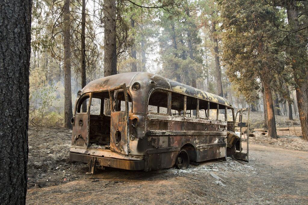 A burned out bus is shown near one of several homes that burned in the recent King fire near Icehouse in El Dorado County on Friday, Sept. 19, 2014. (AP Photo/The Sacramento Bee, Randall Benton)