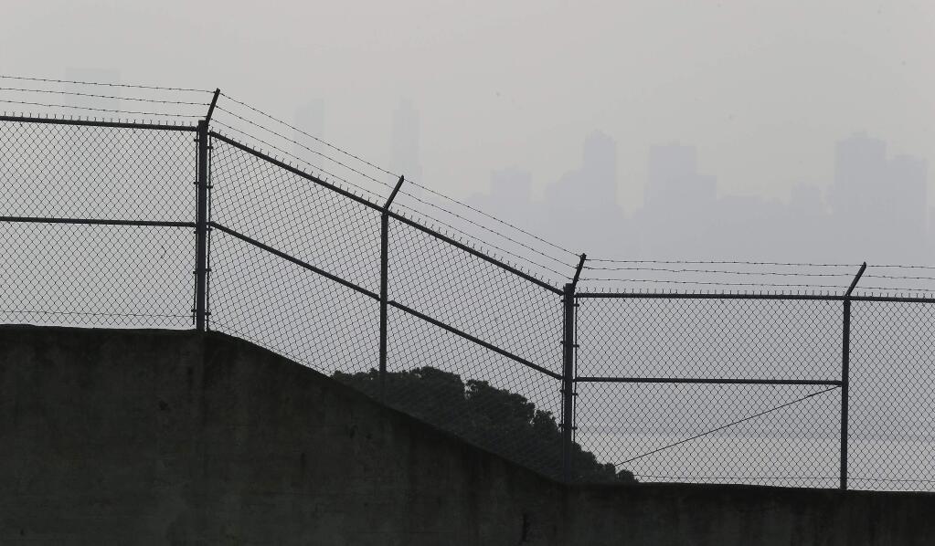 The skyline is obscured by smoke and haze from wildfires and is barely visible behind the prison exercise yard fence on Alcatraz Island Thursday, Nov. 15, 2018, in San Francisco. Recurring wildfires are sparking concern among medical experts about potentially major health consequences. Worsening asthma, lung disease and even heart attacks in heart disease patients have all been linked with previous fires. But blazes that used to be seasonal are happening nearly year-round and increasingly spreading into cities. That's exposing many more people to choking smoke that contains many of the same toxic ingredients as urban air pollution. (AP Photo/Eric Risberg)