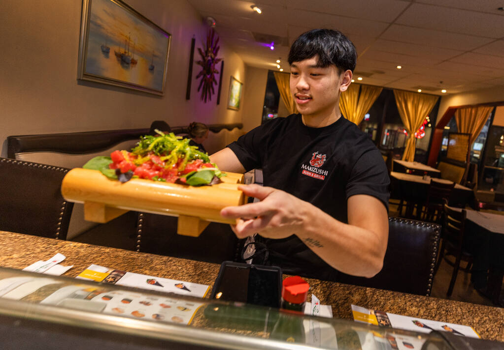 Robert Phouthavong, 18, owner of Makizushi in Santa Rosa, delivers an order to customers, Tuesday, Jan. 3, 2023. Robert and his father Southavichit opened the restaurant after learning the business at Hana Sushi in Sebastopol. (John Burgess/The Press Democrat)