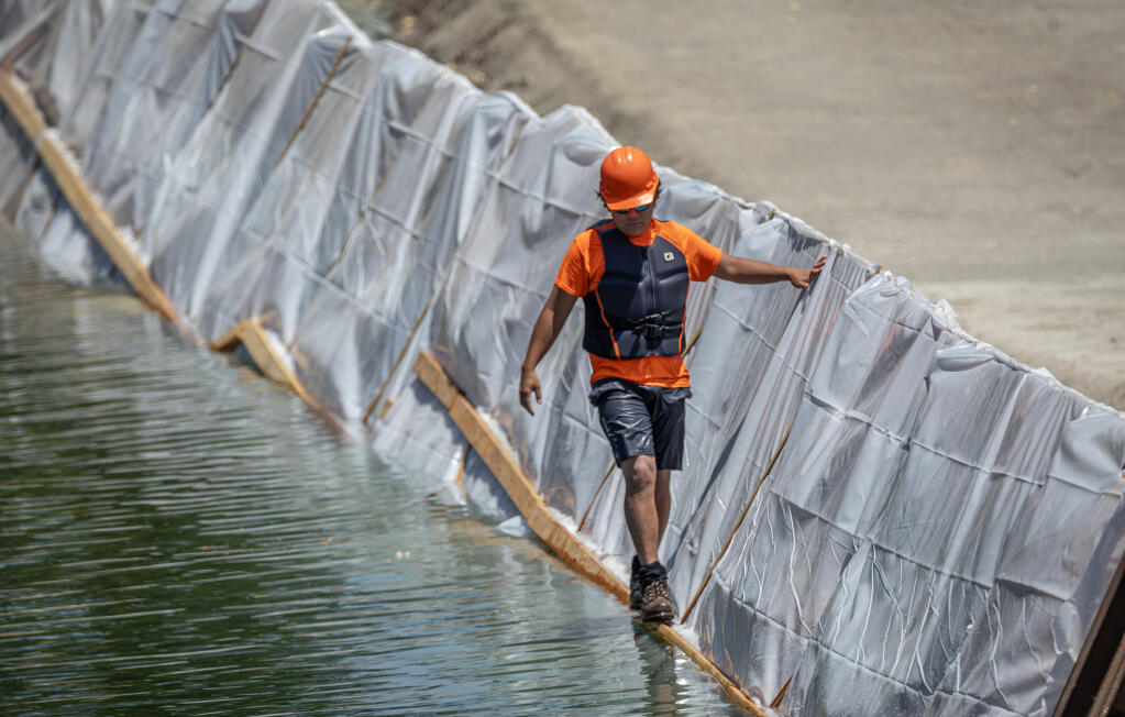 A walkway allows crews to quickly transverse a constructed dam as work continues on the Healdsburg Memorial Beach dam which has not been in place for the last 4 years due to low water levels in the Russian River near downtown Healdsburg, Wednesday June, 27, 2023. (Chad Surmick / The Press Democrat)
