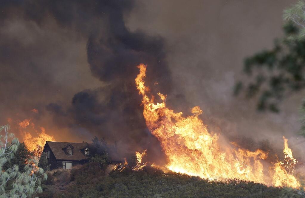 Flames approach a home near Lower Lake on Friday. (JEFF CHIU / Associated Press)