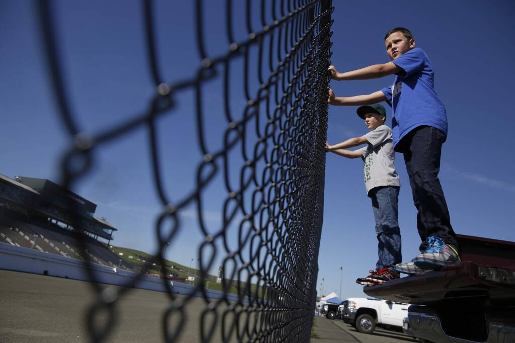 Cody West, 10, front, and his twin brother Justin watch drag racing from the back of a pick-up truck at Sonoma Raceway on Monday, Feb. 16, 2015 in Sonoma. (BETH SCHLANKER/ PD FILE)