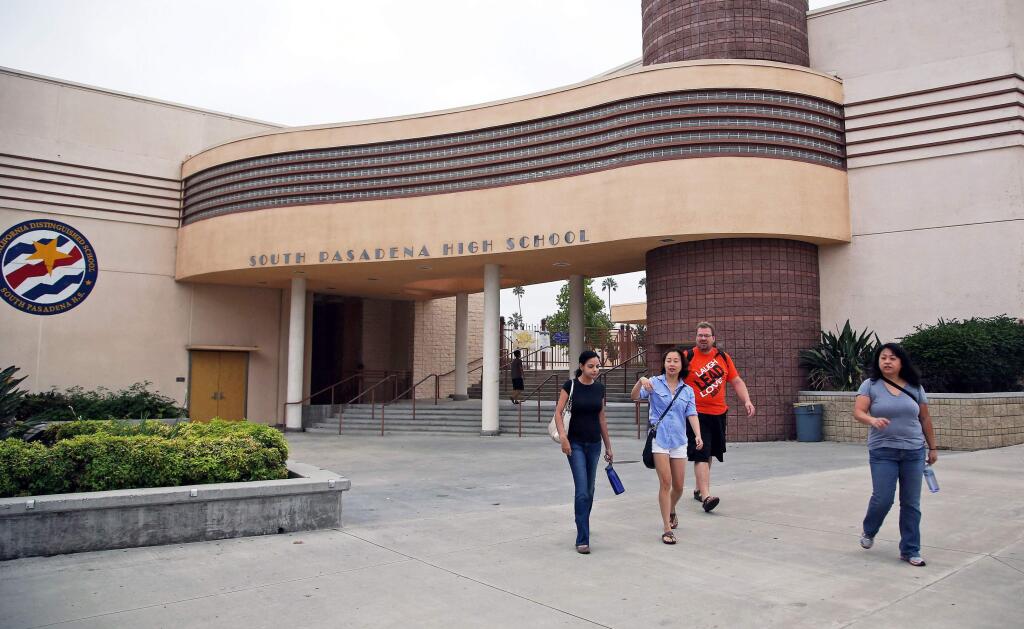 In this Aug. 19, 2014 file photo, people walk past South Pasadena, Calif., High School after authorities announced the arrest of two high school students suspected of planning a massacre at the school after investigators monitored their Internet activities. The two teenage boys arrested in what police call a mass shooting plot at their Los Angeles-area high school were charged Monday, Sept. 8, 2014 with conspiracy to commit murder and conspiracy to commit assault with a deadly weapon. (AP Photo/Nick Ut, File)