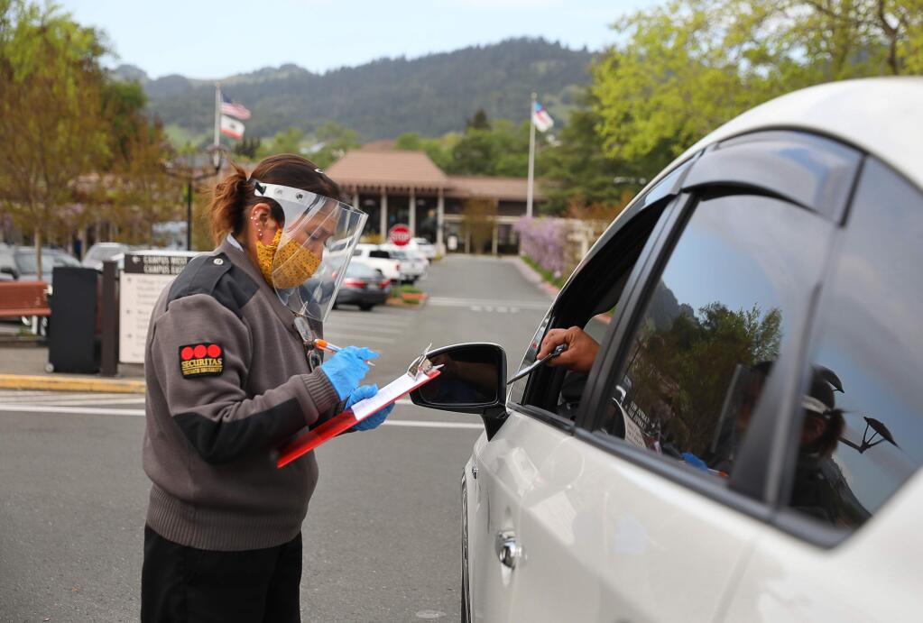 Rosa Castro, with Securitas private security, asks a vendor delivering medicine a series of questions about potential exposure to coronavirus, in Santa Rosa on Thursday, April 16, 2020. (Christopher Chung/ The Press Democrat)