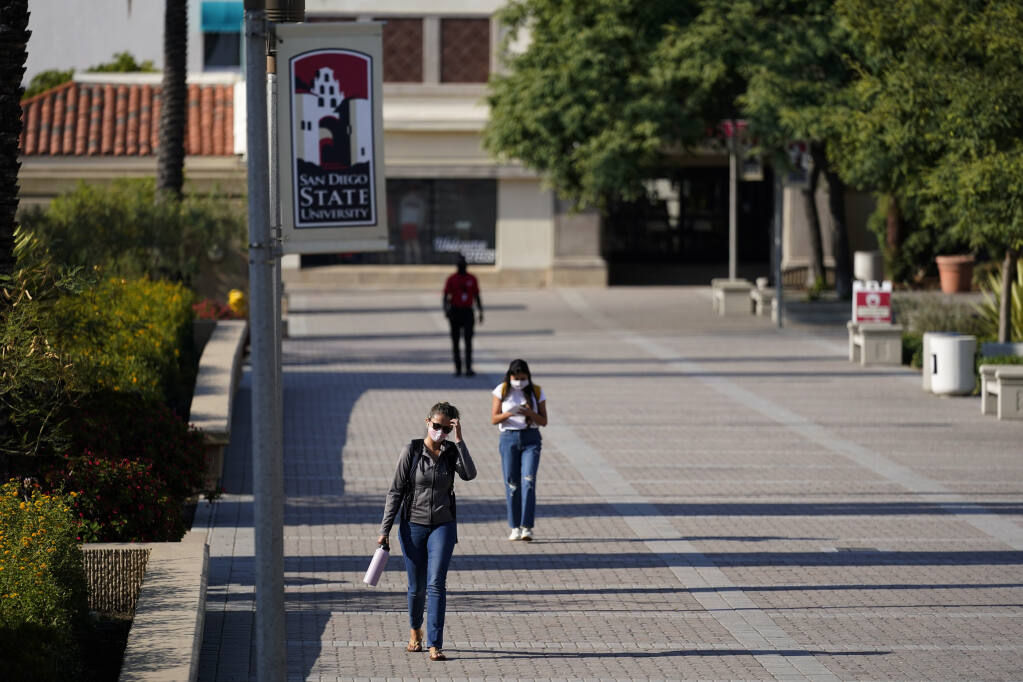 People walk on campus at San Diego State University Wednesday, Sept. 2, 2020, in San Diego. San Diego State University on Wednesday halted in-person classes for a month after dozens of students were infected with the coronavirus. (AP Photo/Gregory Bull)