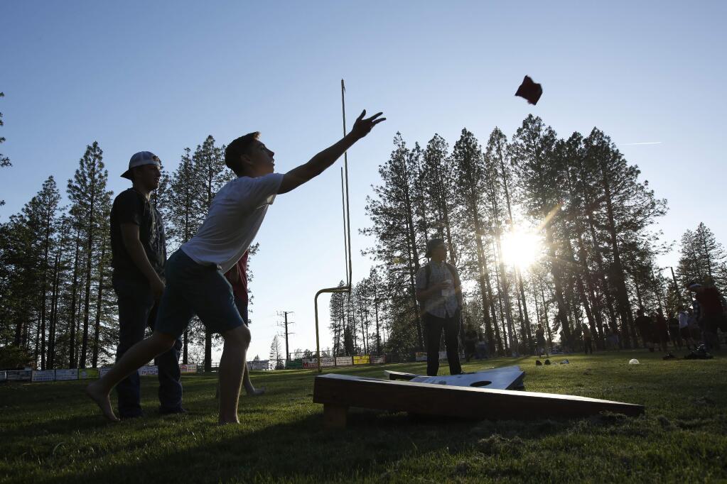Sean Newsom, second from left, tosses a bean bag as he plays cornhole at the Paradise High School in Paradise, Calif., Wednesday, June 5, 2019. After the Camp Fire destroyed his family home in Paradise and his parents relocated to the San Francisco Bay Area, Newsom moved to an apartment with his older brother in Chico to finish his senior year. (AP Photo/Rich Pedroncelli)