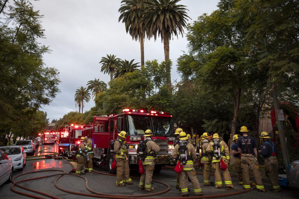 Firefighters respond to an apartment fire in Glendale, Calif. on Thursday, Jan. 16, 2020. The fire injured eight people, including two firefighters who crashed through a collapsing first floor and landed in the basement, authorities said. (Francine Orr/Los Angeles Times via AP)