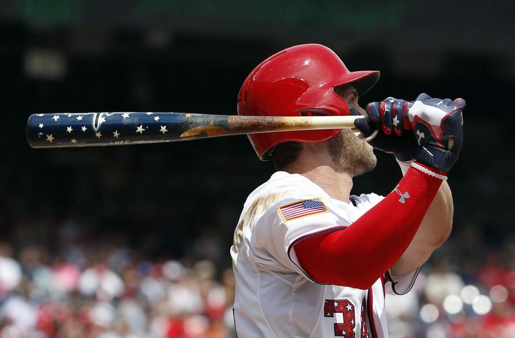Washington Nationals' Bryce Harper (34) watches his two-run homer as he holds his Independence Day themed bat during the first inning of a baseball game against the San Francisco Giants at Nationals Park, Saturday, July 4, 2015, in Washington. (AP Photo/Alex Brandon)
