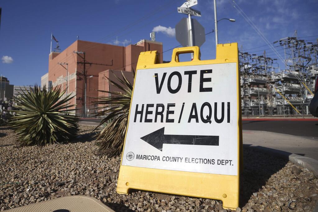 A sign points to a local polling station for the Arizona Democratic presidential preference election Tuesday, March 17, 2020, in Phoenix. (AP Photo/Ross D. Franklin)