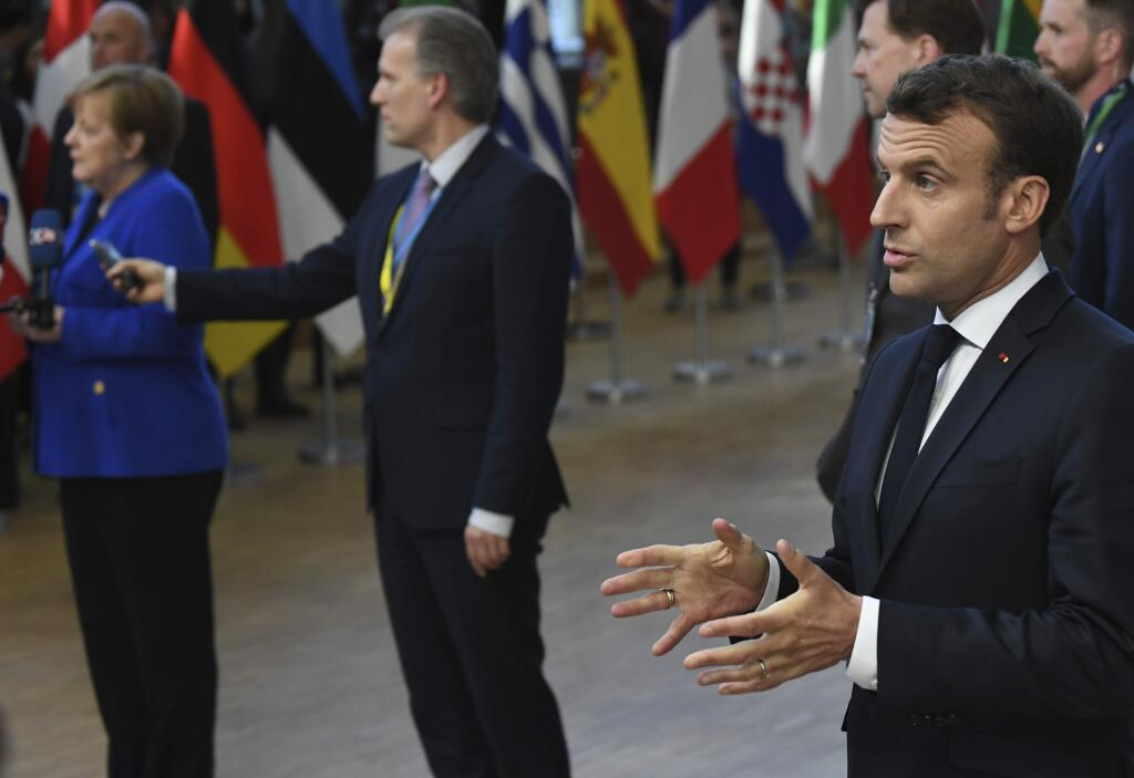 French President Emmanuel Macron, right, speaks with the media as he arrives for an EU summit at the Europa building in Brussels, Wednesday, April 10, 2019. European Union leaders meet Wednesday in Brussels for an emergency summit to discuss a new Brexit extension. (AP Photo/Riccardo Pareggiani)