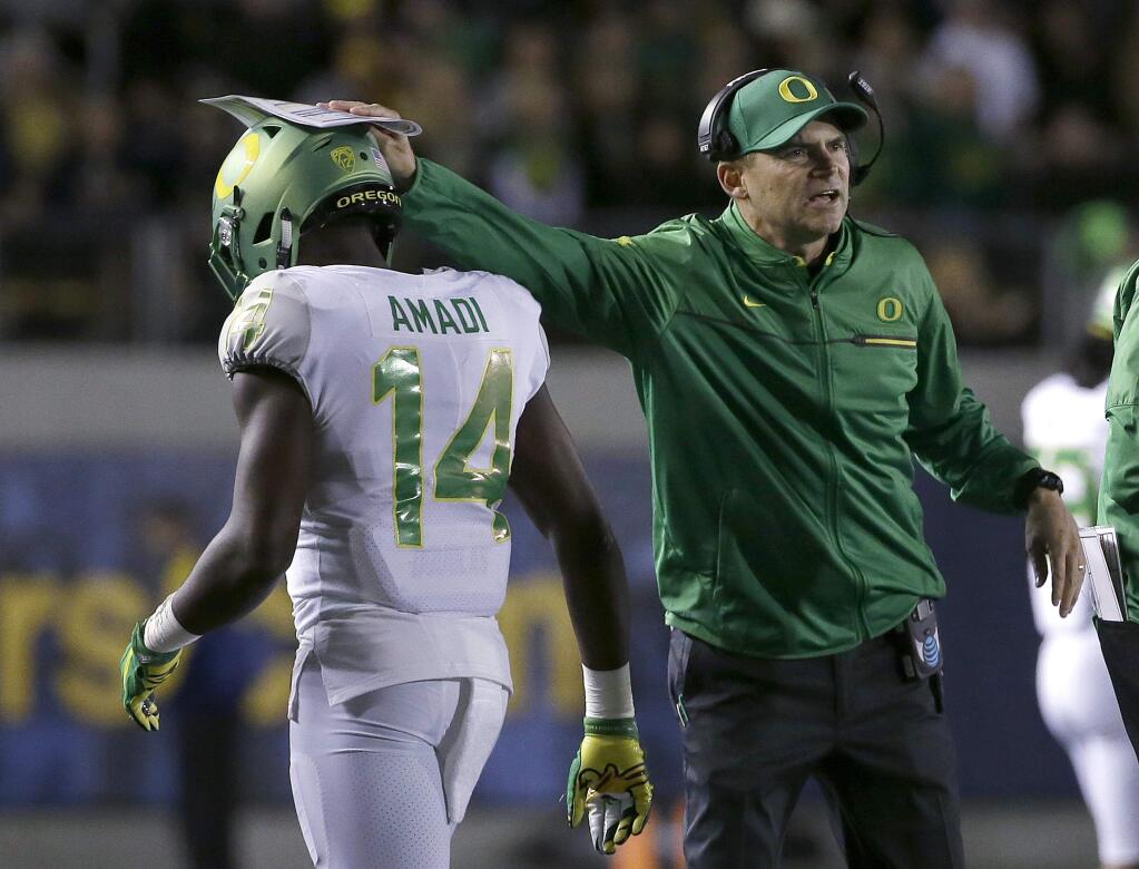 Oregon coach Mark Helfrich, right, pats defensive back Ugo Amadi on the helmet after a California touchdown during the first half of an NCAA college football game in Berkeley, Calif., Friday, Oct. 21, 2016. (AP Photo/Jeff Chiu)