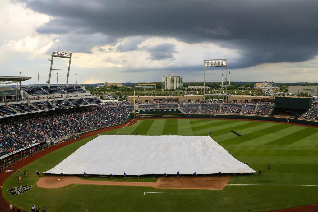Grounds crew members pull the tarp over the playing field at TD Ameritrade Park during a weather delay before Game 3 of the NCAA College World Series finals between Coastal Carolina and Arizona in Omaha, Neb., Wednesday, June 29, 2016. (AP Photo/Nati Harnik)