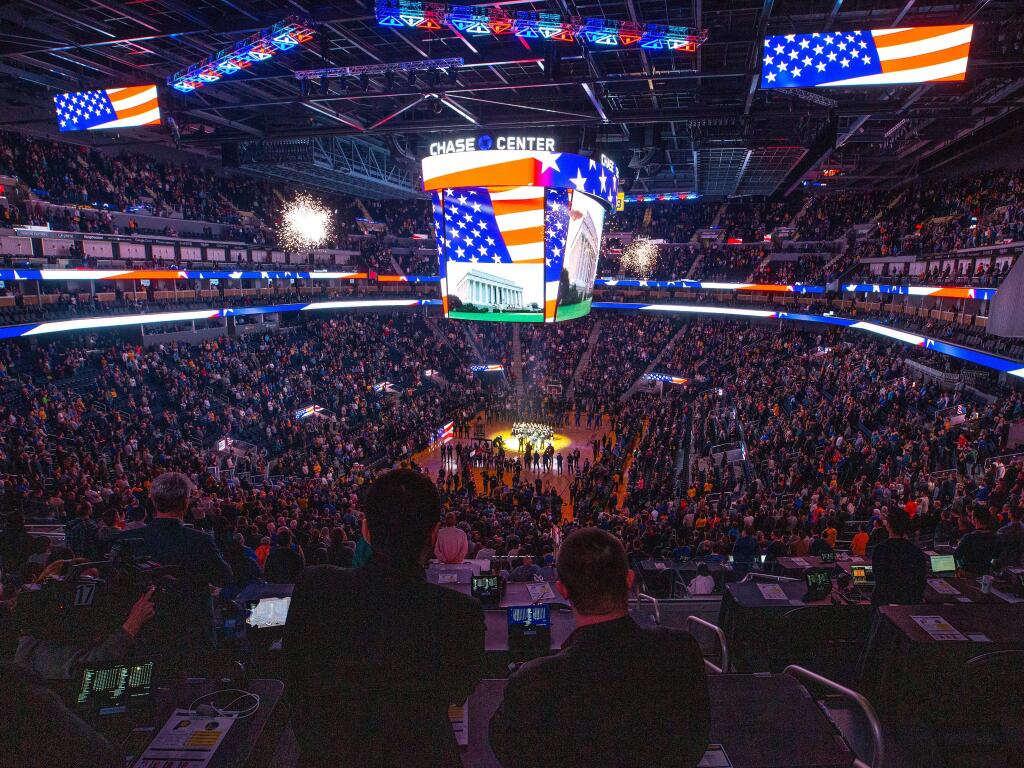 Fireworks burst inside the Chase Center while Mauricio Stillman, center left, and Austin Roach stand at their seats in the press box as the national anthem is performed before a basketball game between the Indiana Pacers and Golden State Warriors in San Francisco on Friday, Jan. 24, 2020. (Alvin Jornada / The Press Democrat)