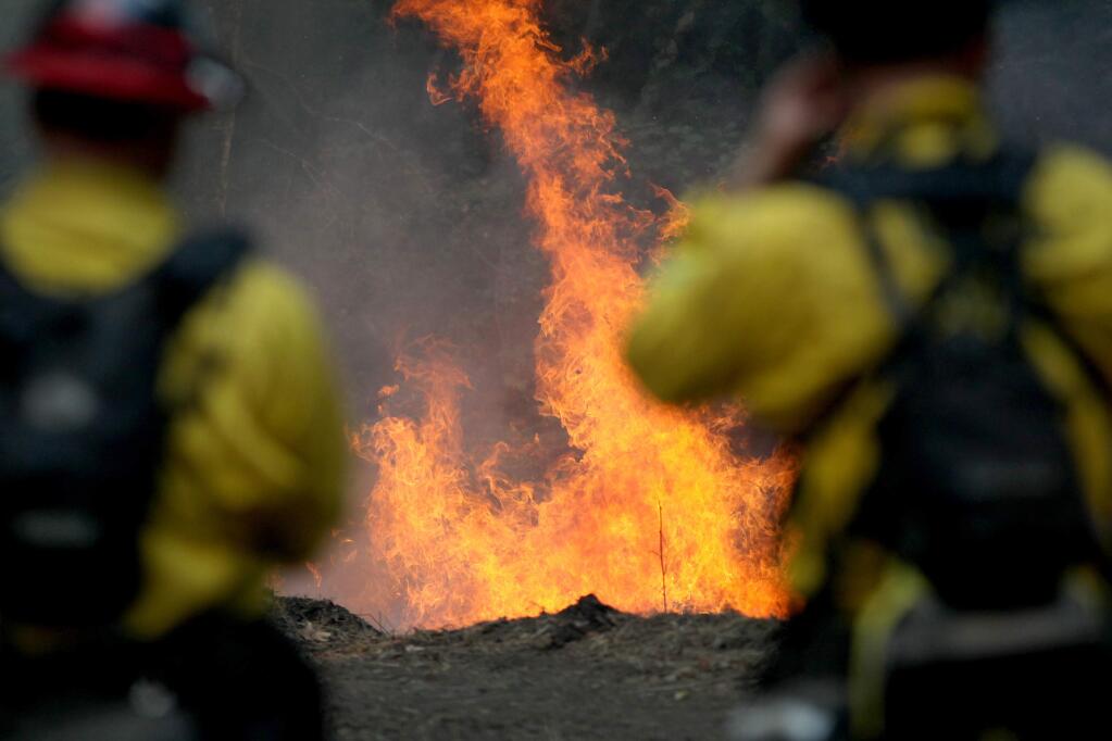 Cal Fire firefighters monitor a burning section of a wildfire on the Garzas Trail in the Santa Lucia Preserve above Carmel Valley, Calif., Thursday, July 28, 2016. Firefighters struggled Thursday to get the upper hand on a massive wildfire burning along California's picturesque Big Sur coastline, where anxious residents driven from their homes awaited word on their properties and popular parks and trails closed at the height of tourist season. (Nic Coury/Monterey County Weekly via AP)