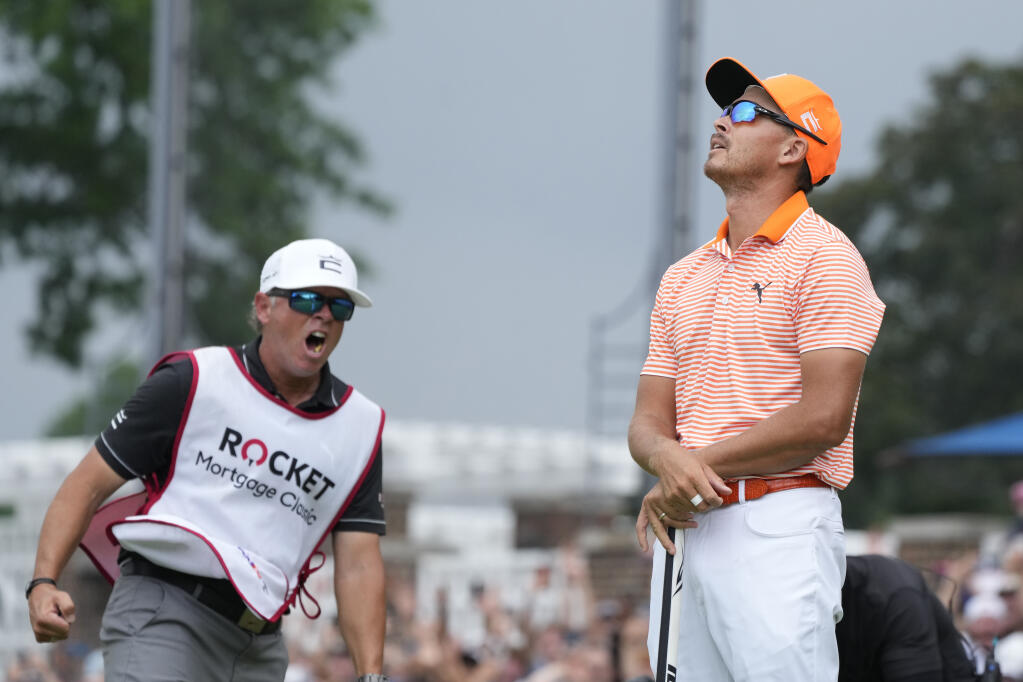 Rickie Fowler looks skyward as his caddie Ricky Romano yells after Fowler's win on the first play-off hole onto the 18th green during the final round of the Rocket Mortgage Classic golf tournament at Detroit Country Club, Sunday, July 2, 2023, in Detroit. (AP Photo/Carlos Osorio)