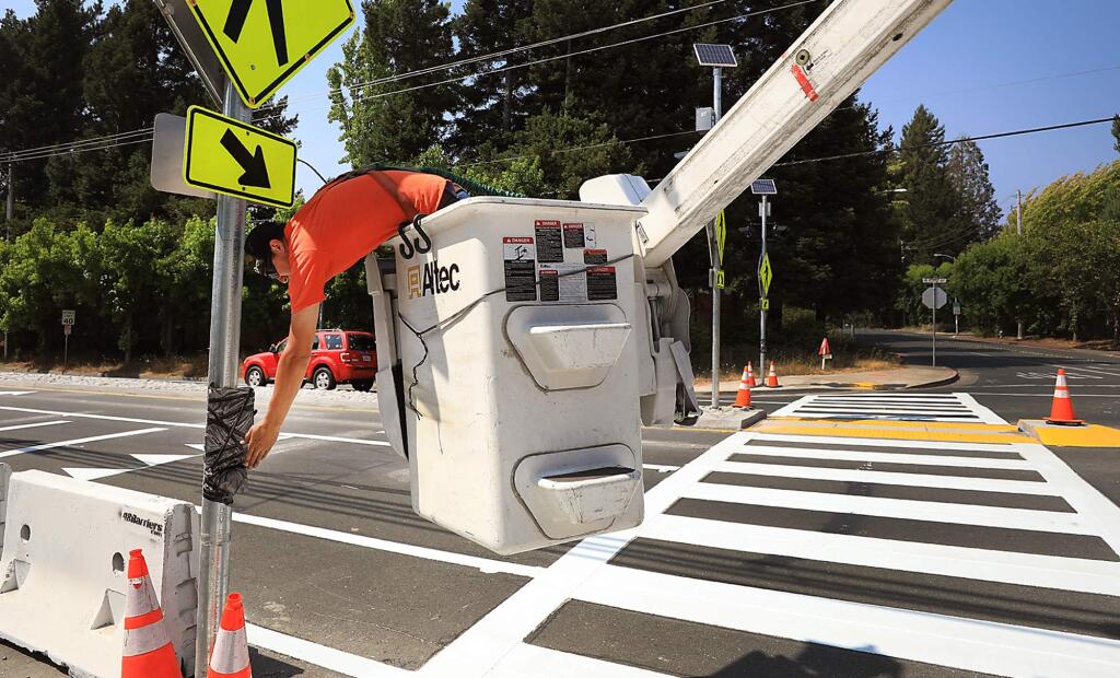 John Crozier of DC Electric of Cotati tests flashing lights after replacing an LED light at Ragle Road and Bodega Highway in Sebastopol, Monday, August 20, 2018 on a new crosswalk warning system. The warning lights, a painted crosswalk and a median strip were installed after a woman in a wheel chair was killed last year while crossing the road. (Kent Porter / The Press Democrat) 2018