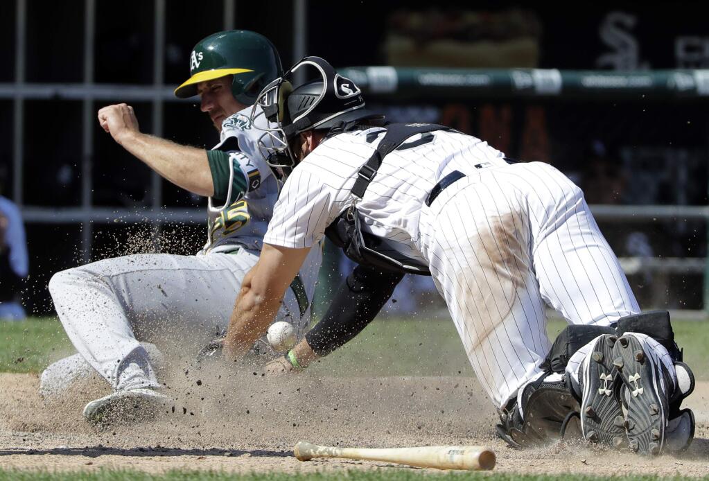 The Oakland Athletics' Stephen Piscotty, left, scores on a single by Nick Martini as Chicago White Sox catcher Kevan Smith misses the ball during the eighth inning Saturday, June 23, 2018, in Chicago. (AP Photo/Nam Y. Huh)