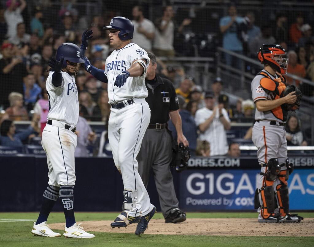 The San Diego Padres' Hunter Renfroe, center, celebrates his two-run home run with Freddy Galvis, left, as San Francisco Giants catcher Nick Hundley stands near the plate during the seventh inning in San Diego, Saturday, April, 14, 2018. (AP Photo/Kyusung Gong)