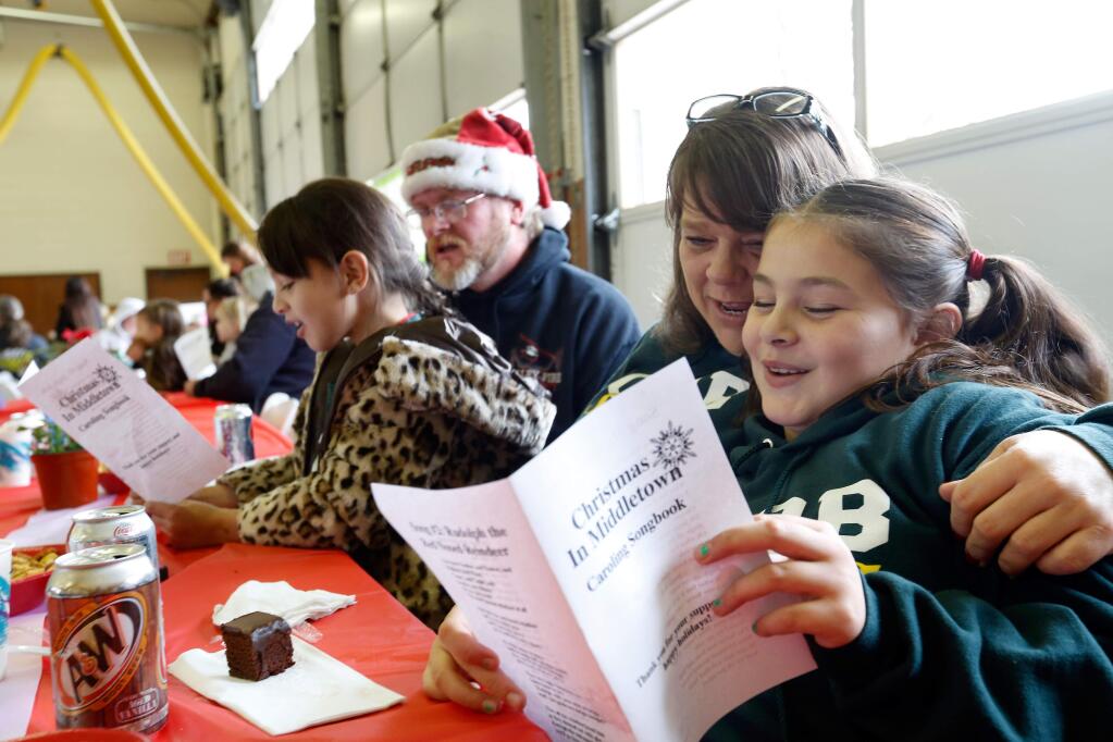 Muira Ruiz, 9, of Cobb, right, sings Christmas carols with her mother Sharon Ruiz, sister Diva Ruiz, 7, and Shawn Ford during the Christmas in Middletown free pasta lunch for Lake County residents at the South Lake County Fire Station in Middletown, California on Saturday, December 12, 2015. (Alvin Jornada / The Press Democrat)
