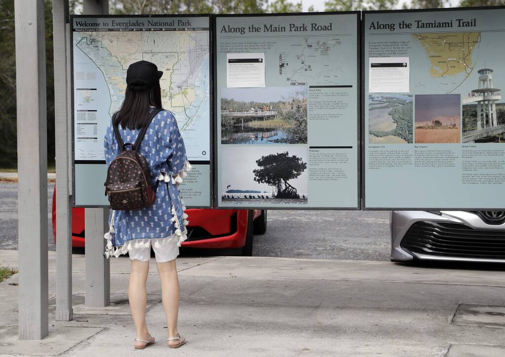 A visitor reads information outside of the Ernest F. Coe Visitor Center in Everglades National Park, Friday, Jan. 4, 2019, in Homestead, Fla. As the partial government shutdown drags on, private organizations, local businesses, volunteers and state governments are putting up the money and manpower to keep national parks across the U.S. open, safe and clean for visitors. (AP Photo/Lynne Sladky)