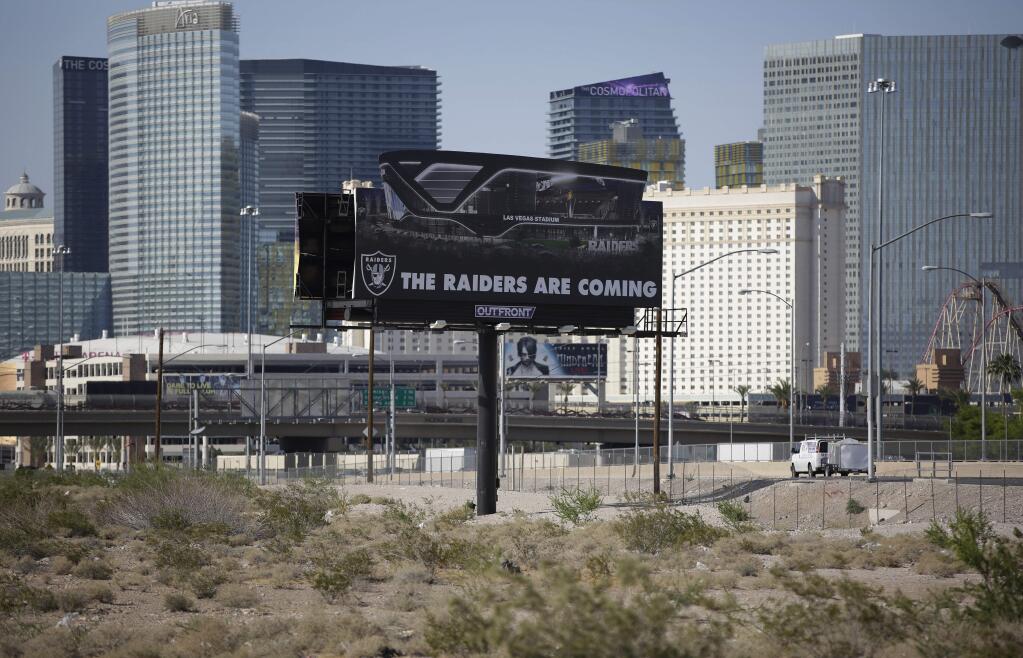 In this May 11, 2017, file photo, a sign advertises the Raiders football team near a site for the team's proposed stadium in Las Vegas. (AP Photo/John Locher, File)